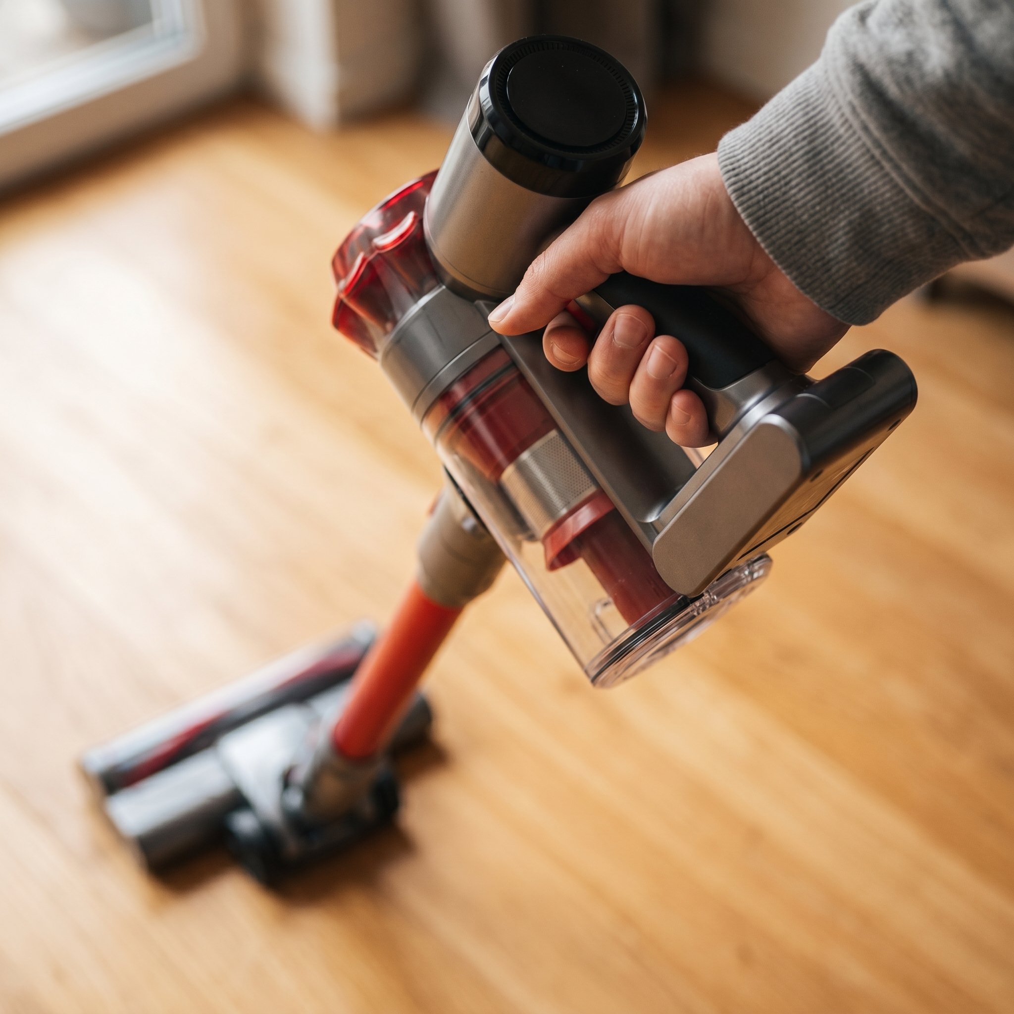 A relaxed hand grips the Nyven vacuum's handle without holding the trigger, demonstrating the trigger-lock convenience.